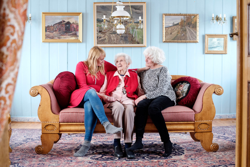 Three generations of women sitting together in a sofa. Photo.