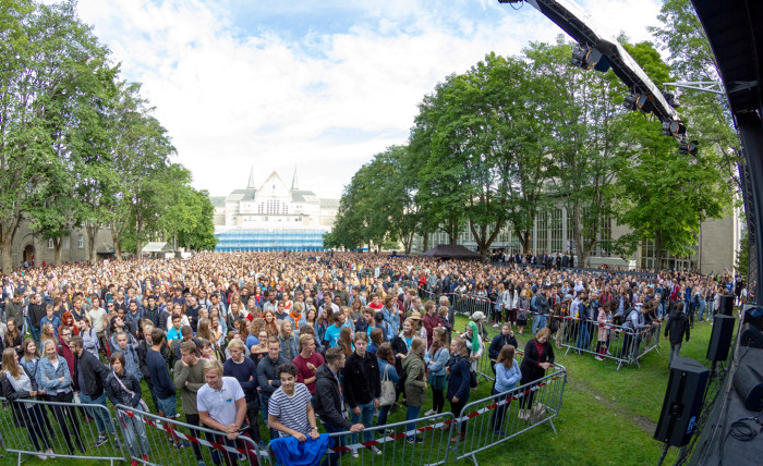 En menneskemengde står foran scenen på plenen under immatrikuleringen 2018 på Gløshaugen. Foto.