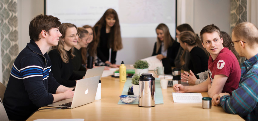 Studenter har undervisning rundt et bord. Foto.