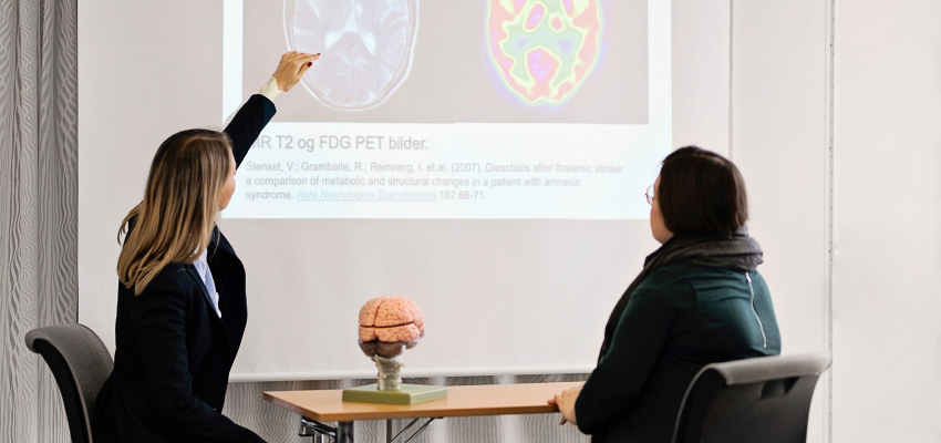 To personer ser på pet-skan-bilder av en hjerne. Foto.