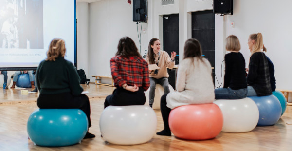Studenter sitter på gummiballer i undervisningssituasjon. Foto