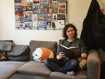 Sosiologistudent Martin sitter i en sofa og leser i en bok. Foto