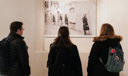 To kvinner og en mann ser på et svart hvitt bilde fra krigen. Foto