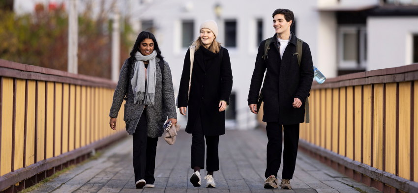Tre studenter går over en bru mot kamera. Foto